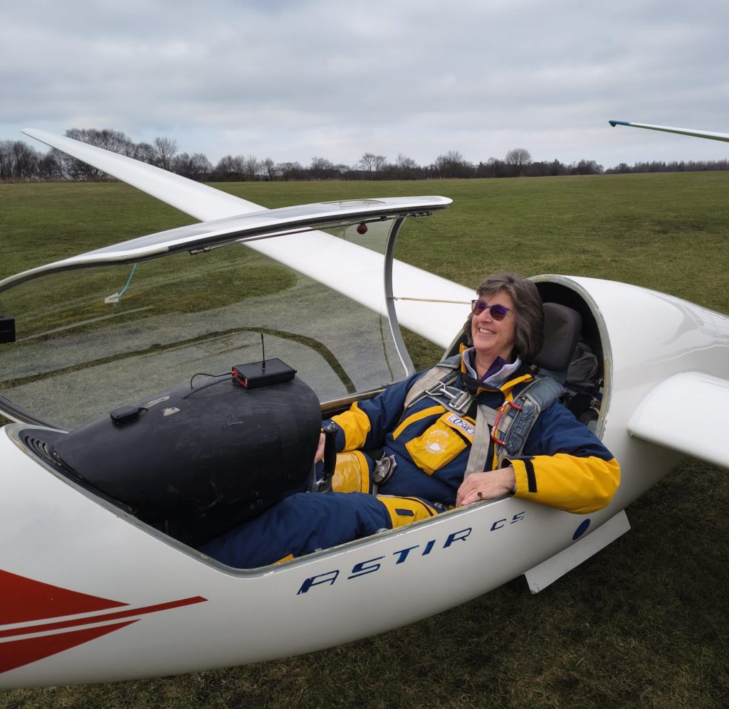 Photo of a female pilot sitting in a single-seat glider, ready to fly.